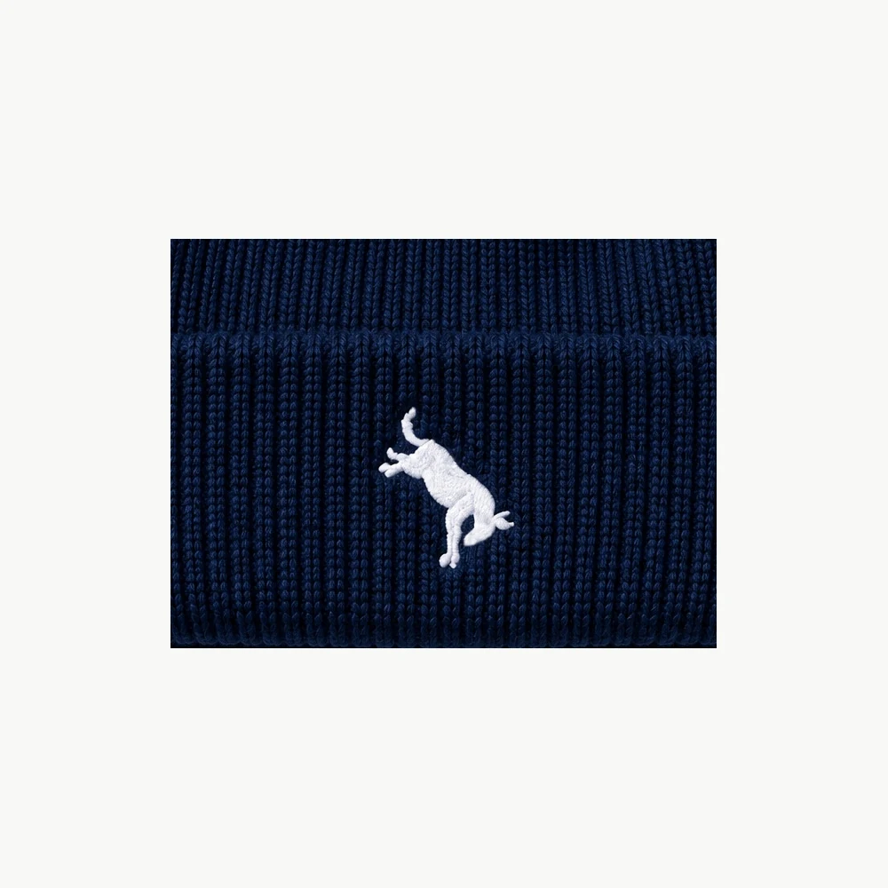 Close-up of the solid white embroidered Hutch logo on the navy knit beanie